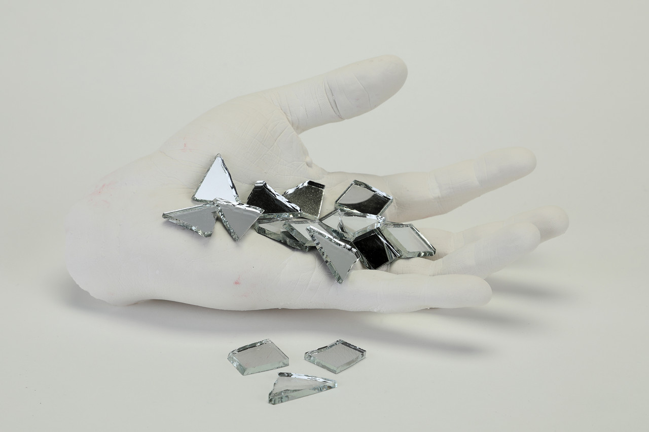 A cast white hand holding a palmful of broken mirror
